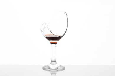 Photo of Broken glass with wine on table against white background