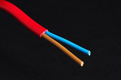 Photo of Red stripped electrical wire on black background, closeup