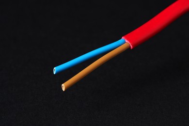 Photo of Red stripped electrical wire on black background, closeup