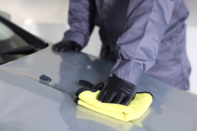 Photo of Man polishing car hood with rag indoors, closeup