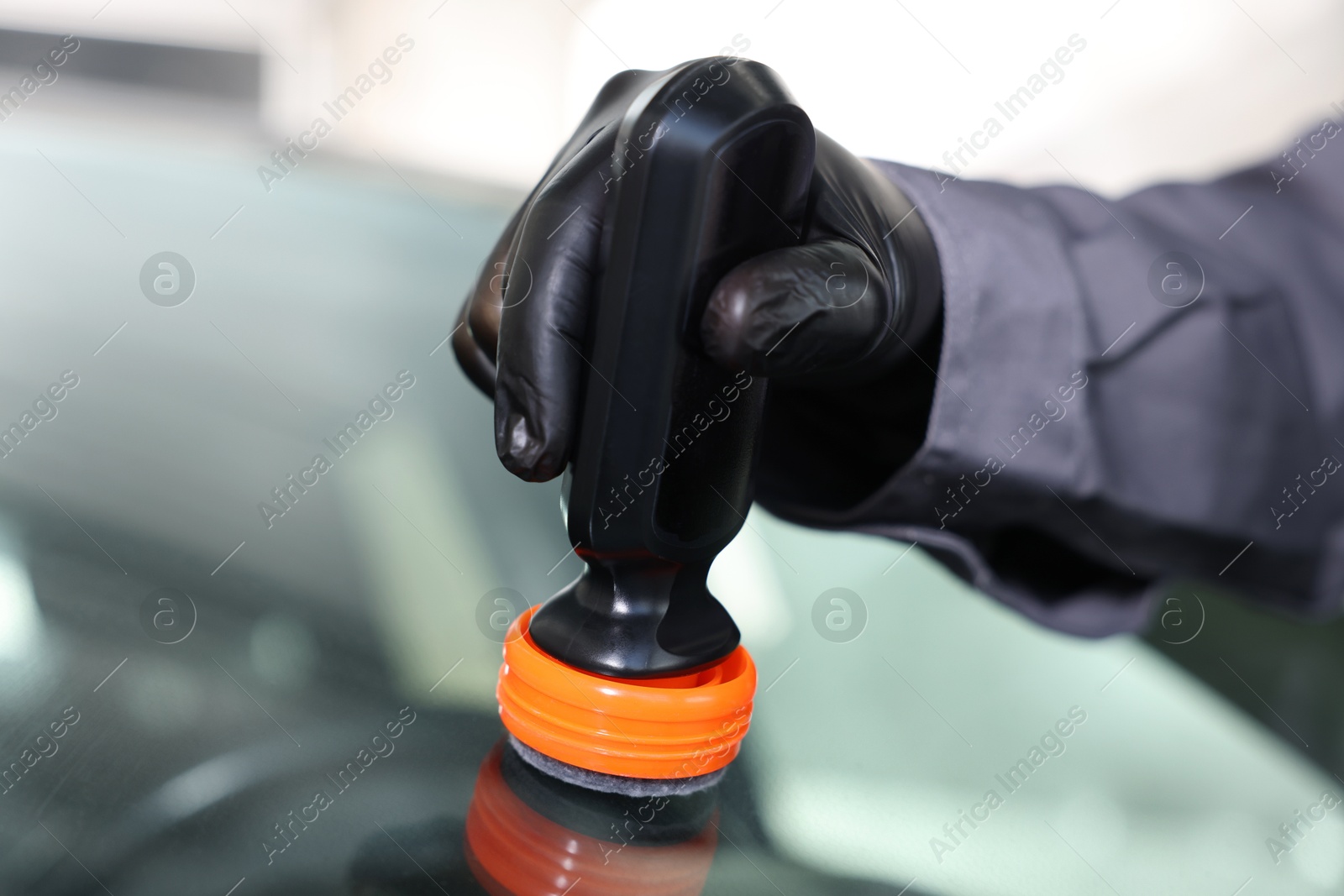 Photo of Man polishing car windshield indoors, closeup view