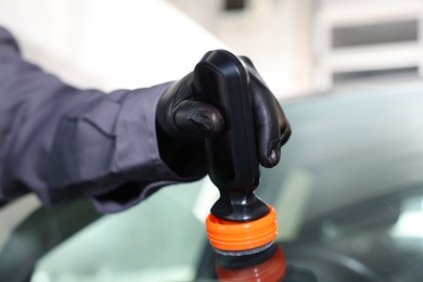 Photo of Man polishing car windshield indoors, closeup view