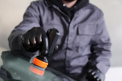 Photo of Man polishing car windshield indoors, closeup view