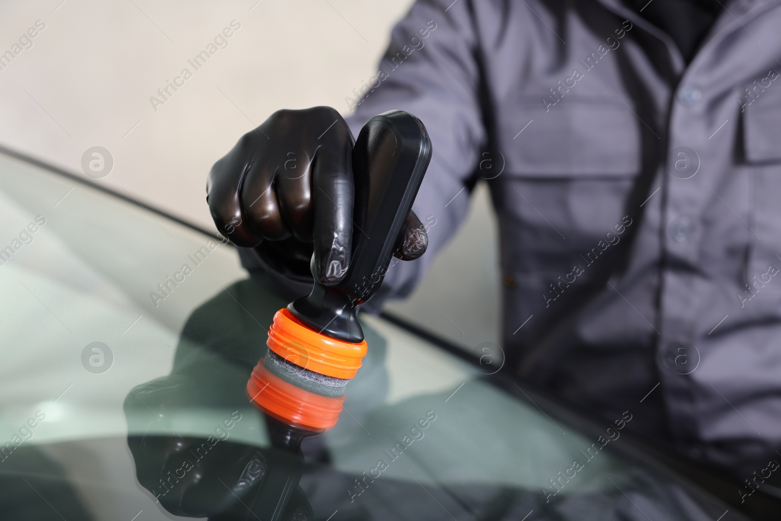 Photo of Man polishing car windshield indoors, closeup view