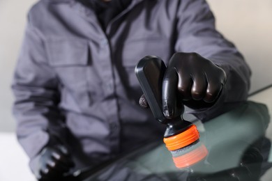 Photo of Man polishing car windshield indoors, closeup view