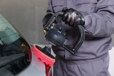 Photo of Man polishing car with orbital polisher indoors, closeup