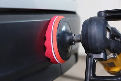 Photo of Man polishing car with orbital polisher indoors, closeup