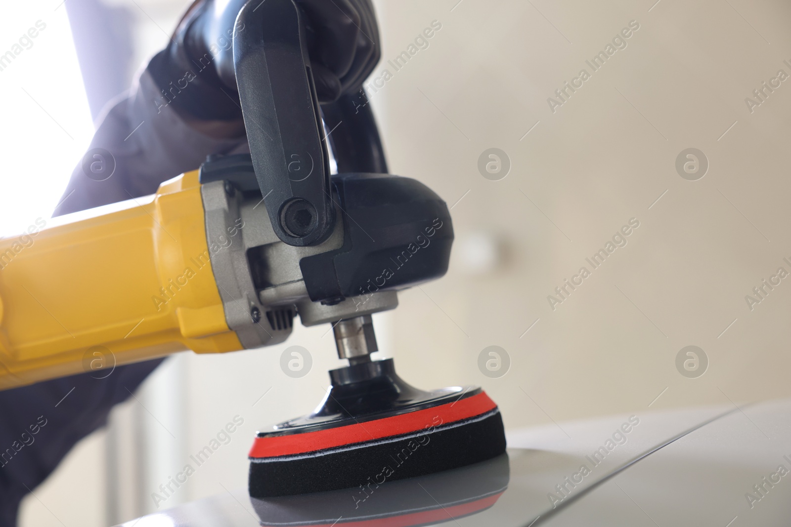 Photo of Man polishing car with orbital polisher indoors, closeup. Space for text