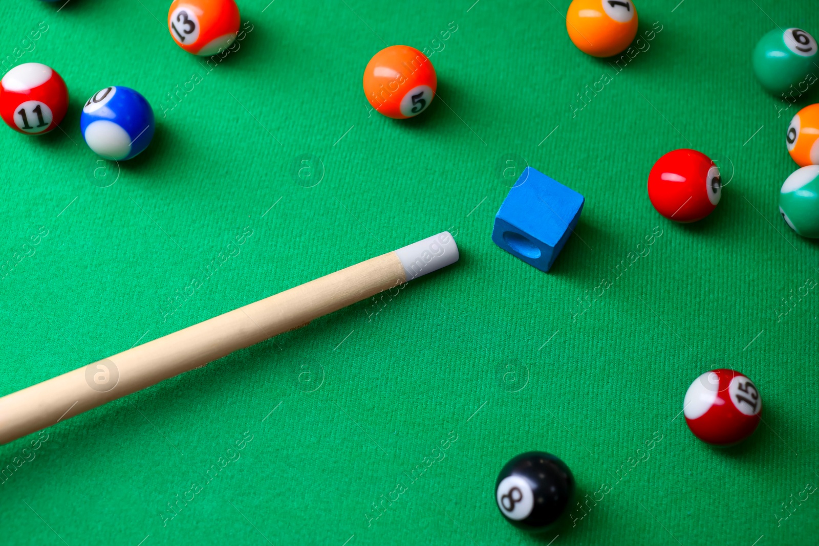 Photo of Many colorful billiard balls, cue and chalk on green table, above view