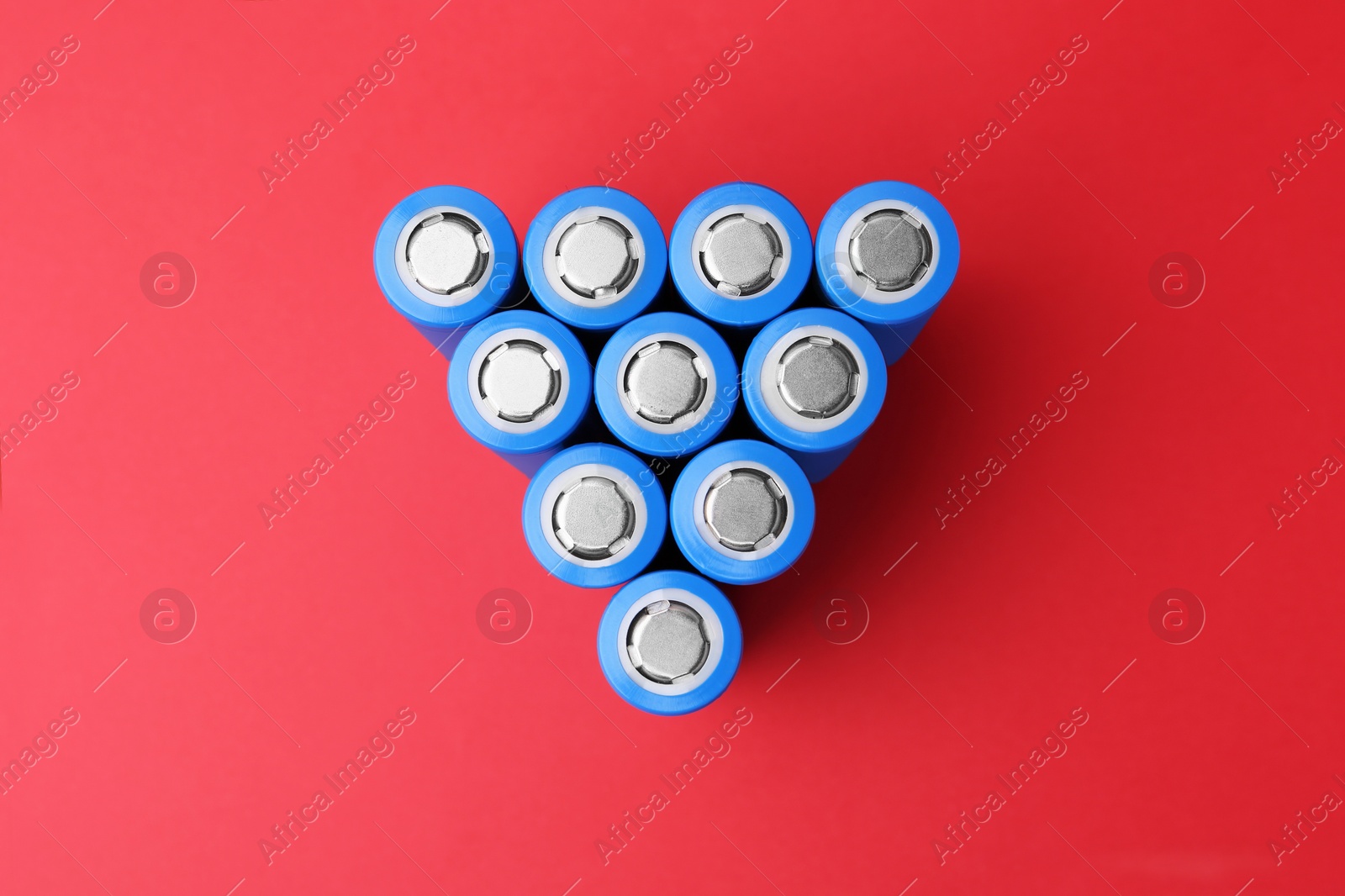 Photo of Many AA cell batteries on red background, top view