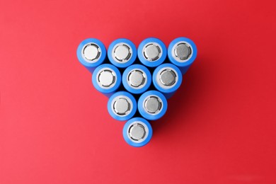 Photo of Many AA cell batteries on red background, top view