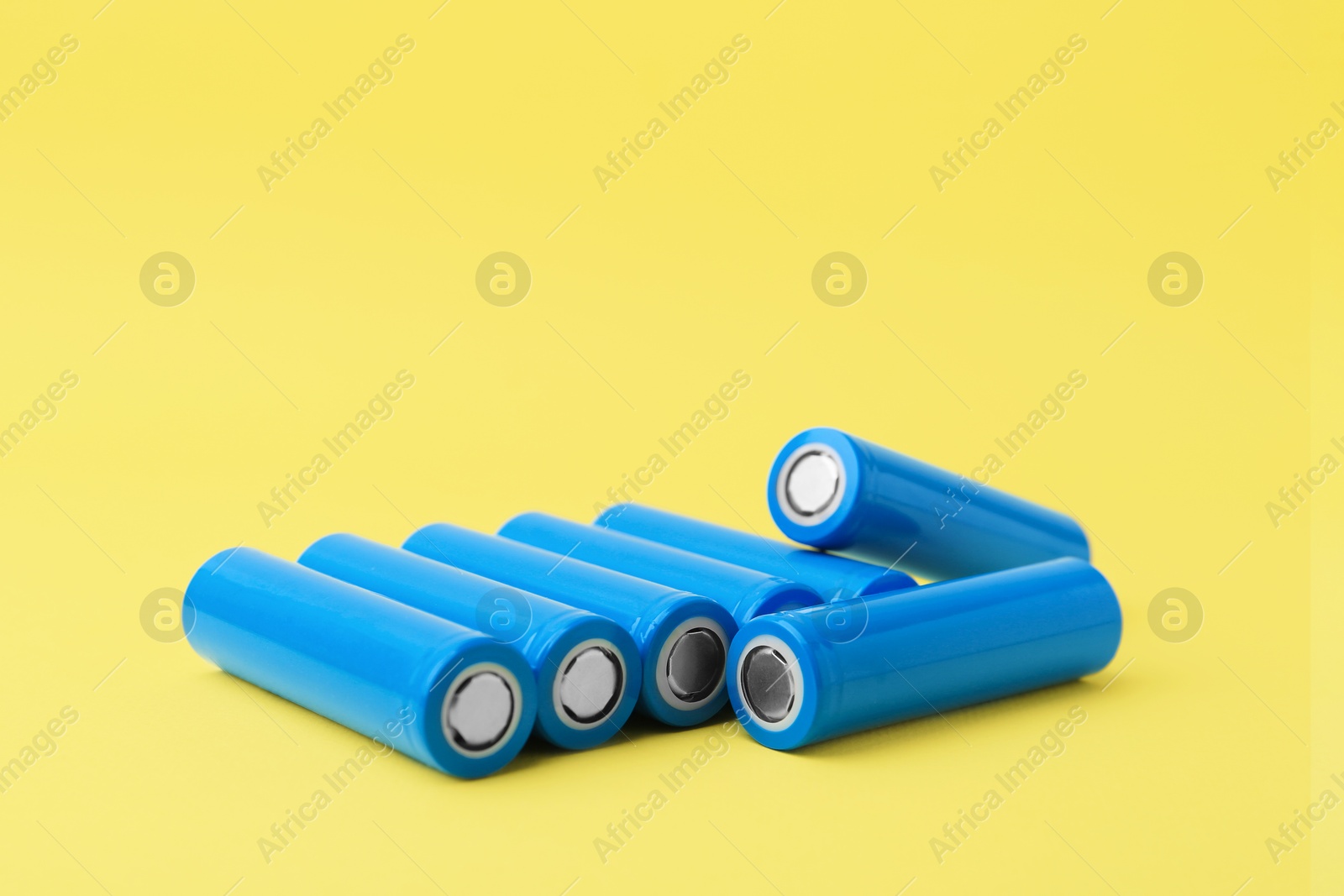 Photo of Many AA cell batteries on yellow background. Space for text