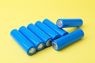 Photo of Many AA cell batteries on yellow background, closeup