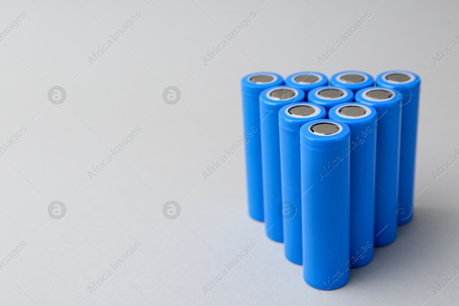 Photo of Many AA cell batteries on light grey background, closeup. Space for text