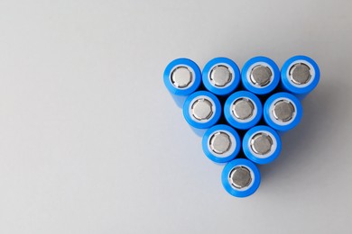 Photo of Many AA cell batteries on light grey background, top view. Space for text