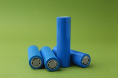 Photo of Many AA cell batteries on green background, closeup. Space for text