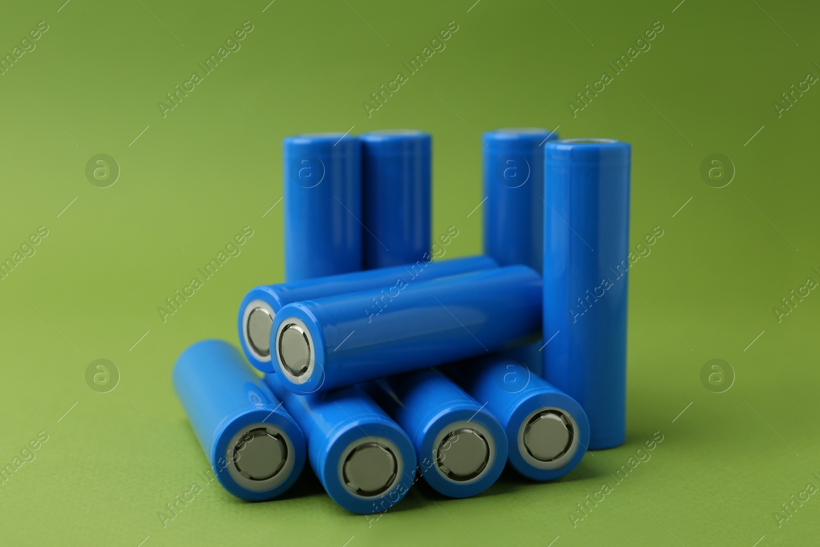 Photo of Many AA cell batteries on green background, closeup