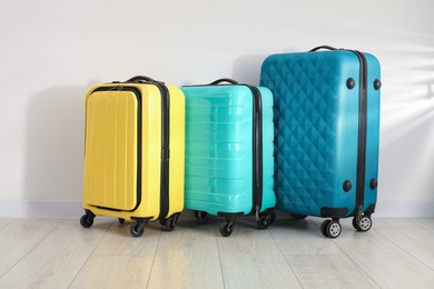 Photo of Colorful suitcases on floor near white wall