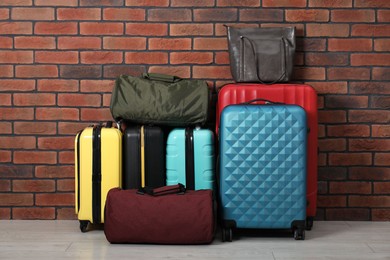 Photo of Many colorful suitcases and bags on floor near brick wall