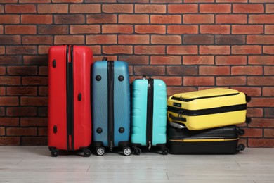 Photo of Many colorful suitcases on floor near brick wall