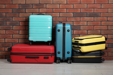 Photo of Many colorful suitcases on floor near brick wall