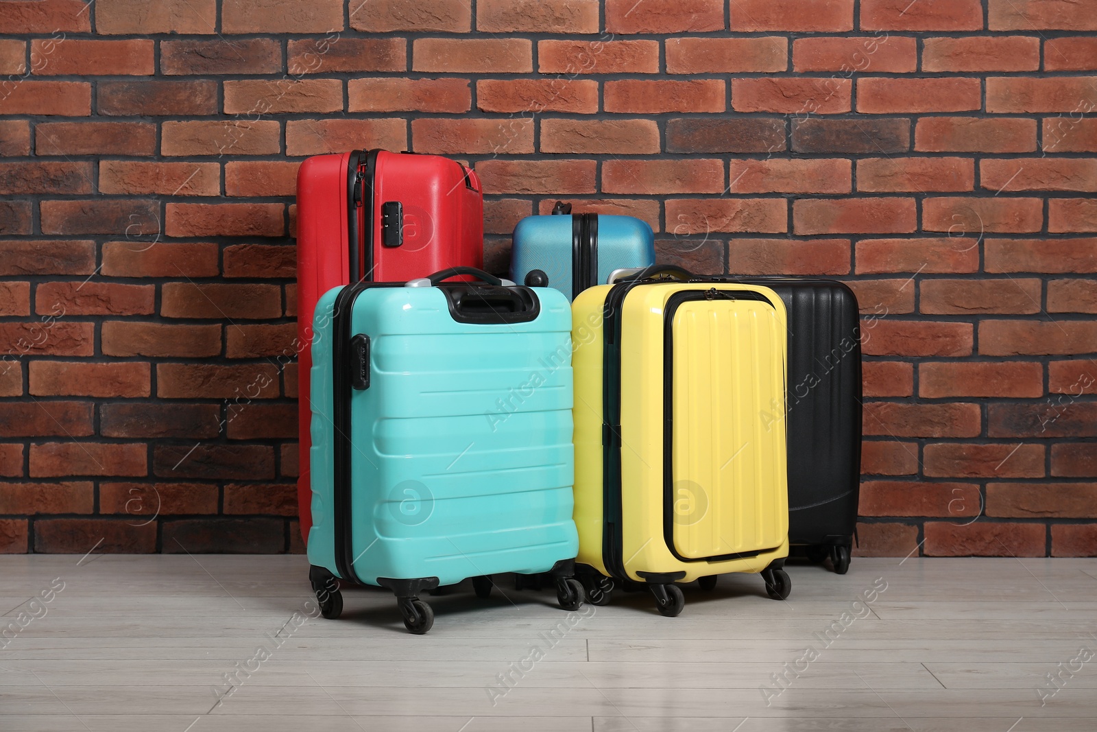 Photo of Many colorful suitcases on floor near brick wall