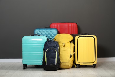 Photo of Colorful suitcases and backpacks on floor near black wall