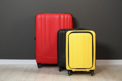 Photo of Colorful suitcases on floor near black wall