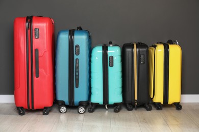 Photo of Colorful suitcases on floor near black wall