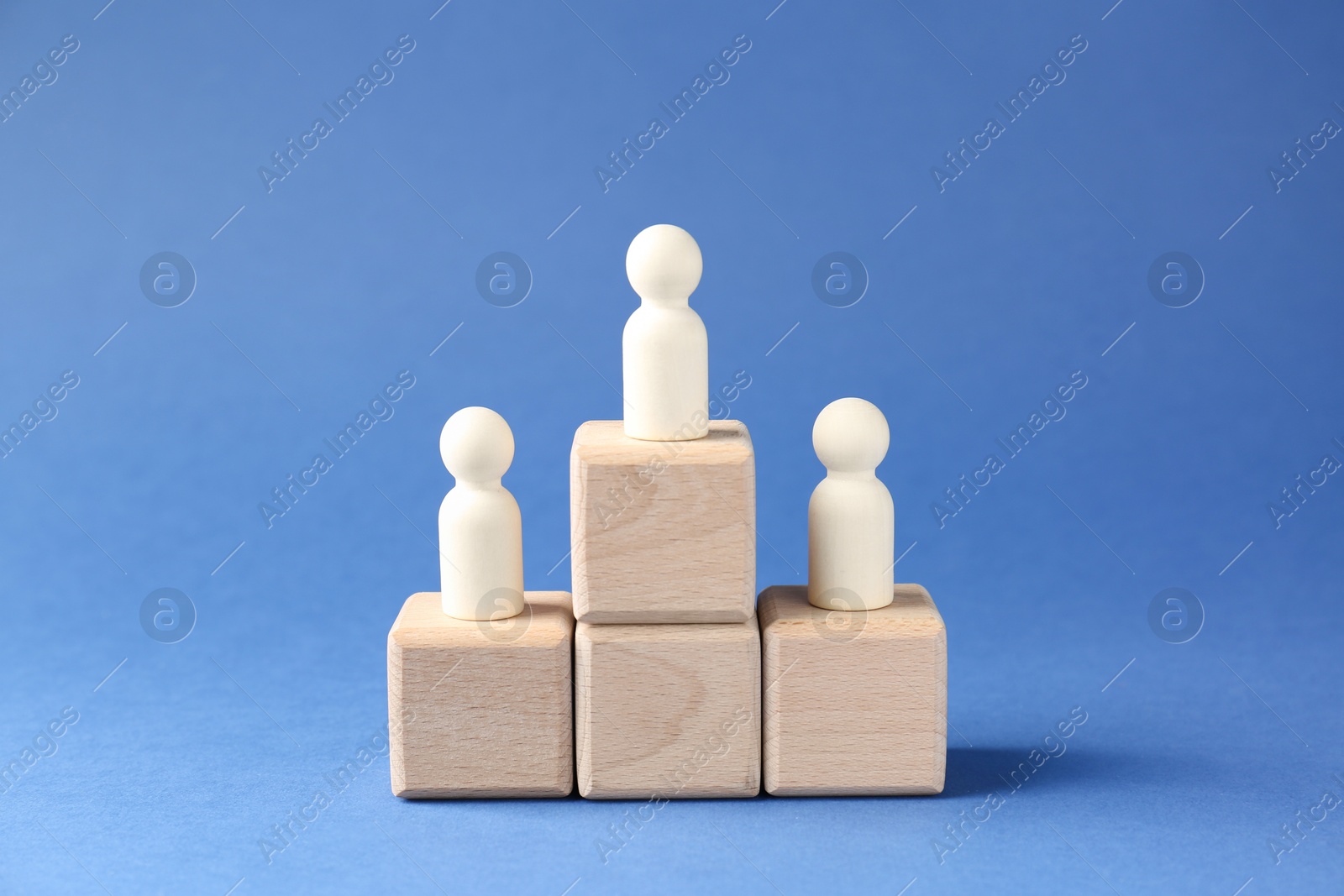 Photo of Competition concept. Human figures on wooden cubes against blue background