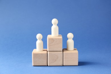 Photo of Competition concept. Human figures on wooden cubes against blue background