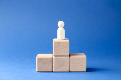 Photo of Competition concept. Human figure on wooden cubes against blue background