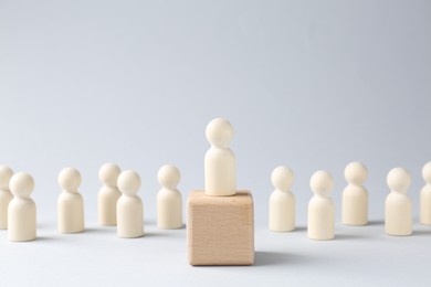 Photo of Competition concept. Human figure on wooden cube and other ones behind against light background, space for text