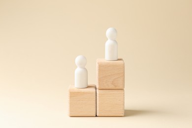 Competition concept. Human figures on wooden cubes against beige background