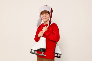 Photo of Little boy in hat with ice skates on light grey background