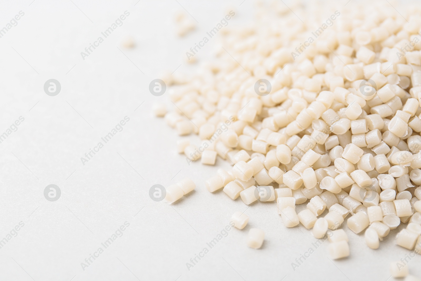 Photo of Pile of plastic granules on white background, closeup. Space for text