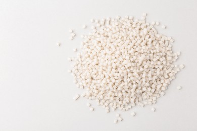 Photo of Pile of plastic granules on white background, top view. Space for text