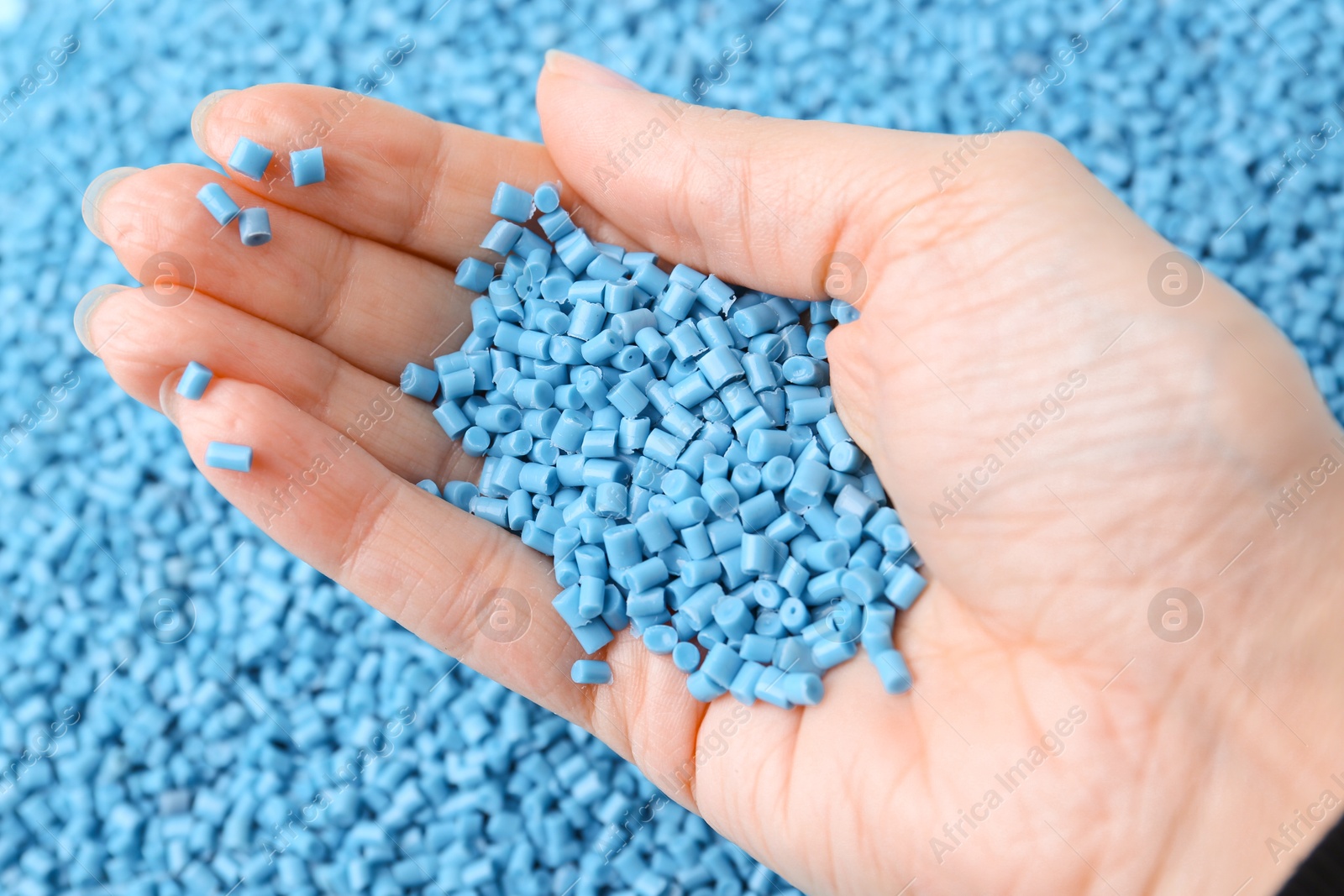 Photo of Woman with light blue plastic granules on blurred background, closeup