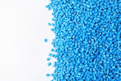 Photo of Pile of light blue plastic granules on white background, top view. Space for text