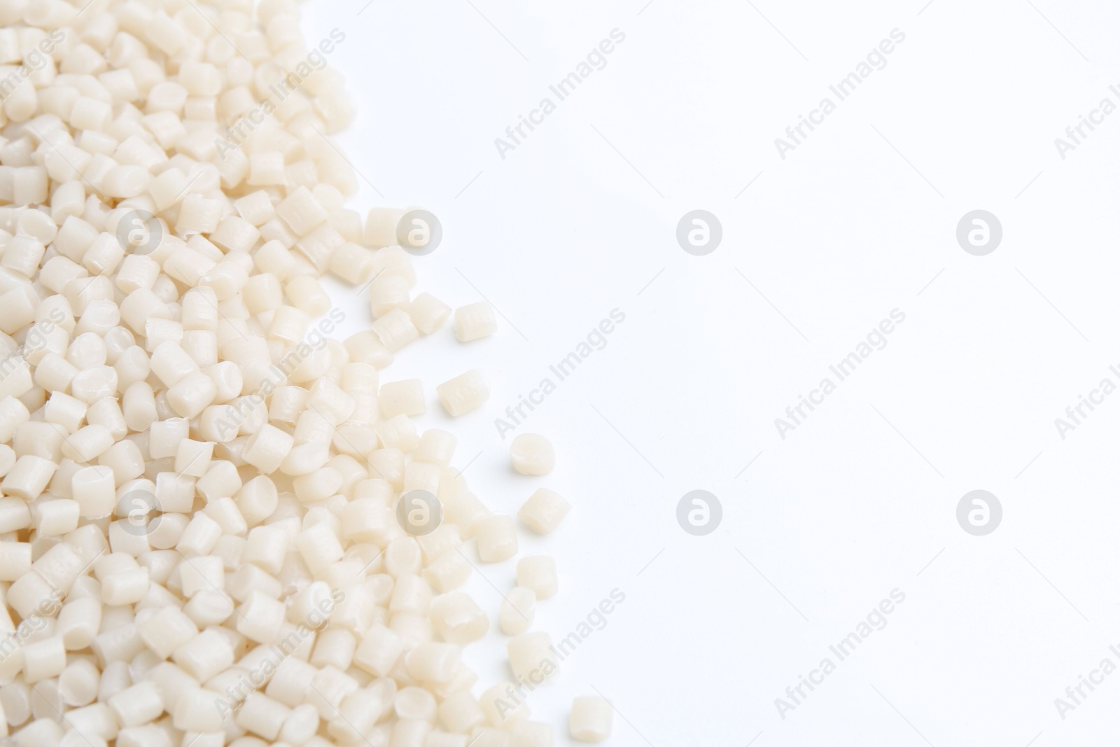 Photo of Pile of plastic granules on white background, closeup. Space for text