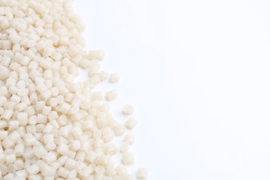 Photo of Pile of plastic granules on white background, closeup. Space for text