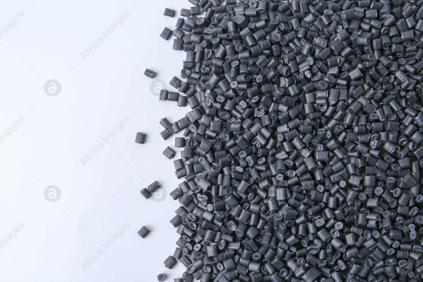 Photo of Pile of black plastic granules on white background, top view. Space for text