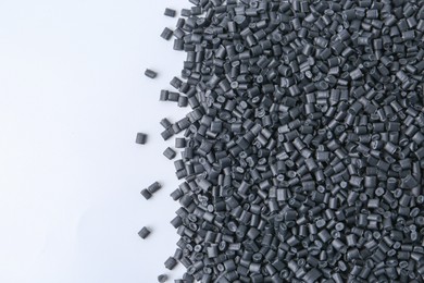 Photo of Pile of black plastic granules on white background, top view. Space for text