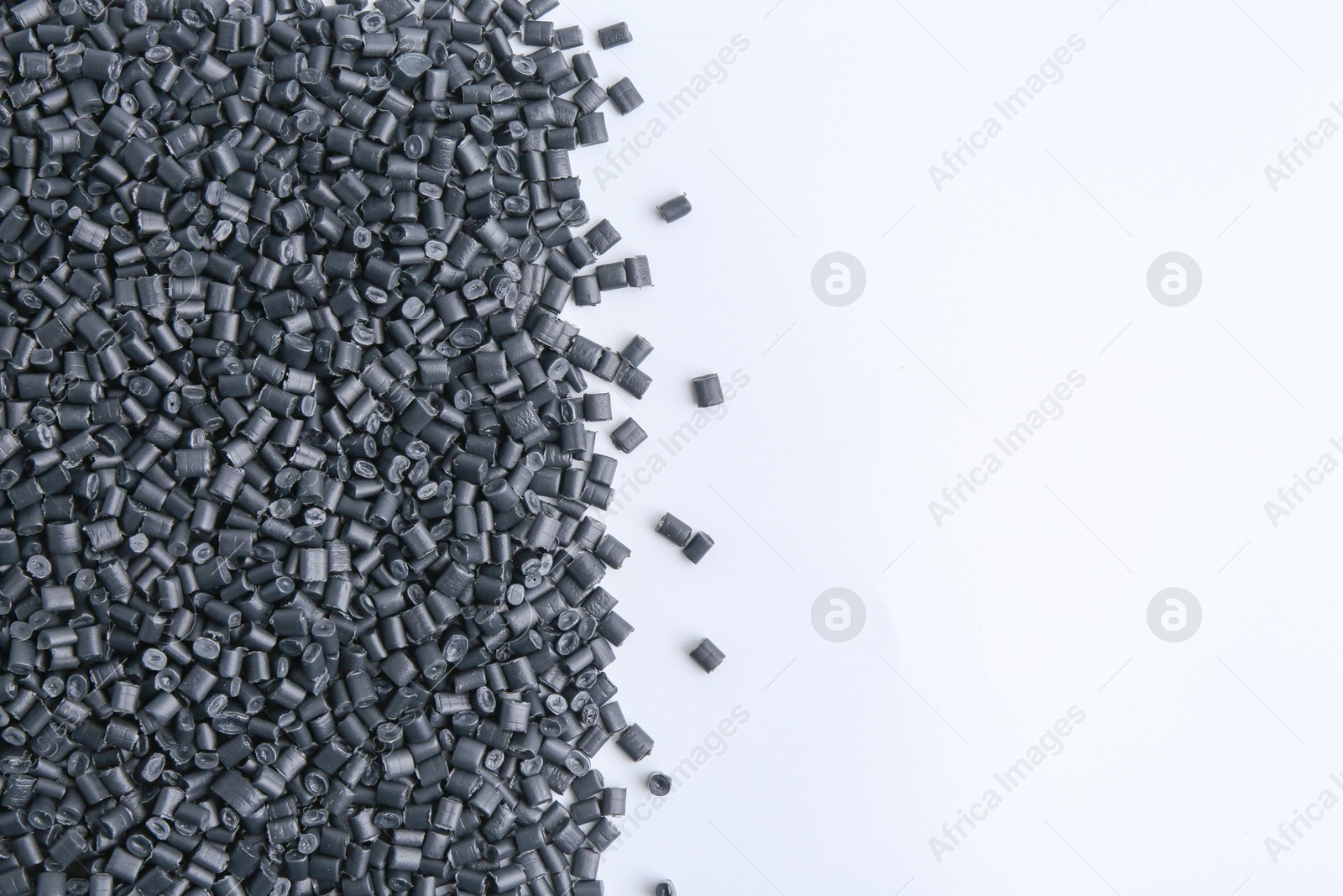 Photo of Pile of black plastic granules on white background, top view. Space for text