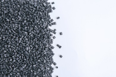 Photo of Pile of black plastic granules on white background, top view. Space for text