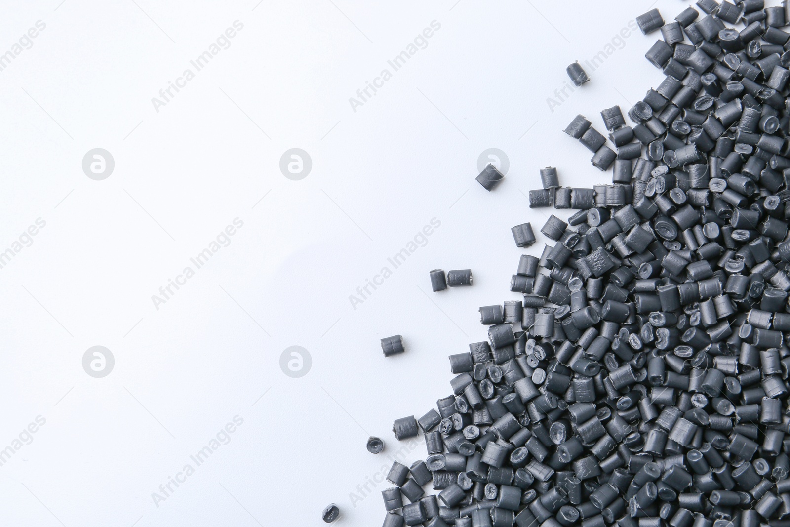 Photo of Pile of black plastic granules on white background, top view. Space for text