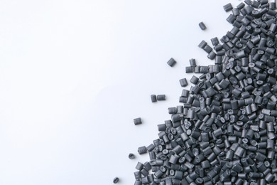 Photo of Pile of black plastic granules on white background, top view. Space for text