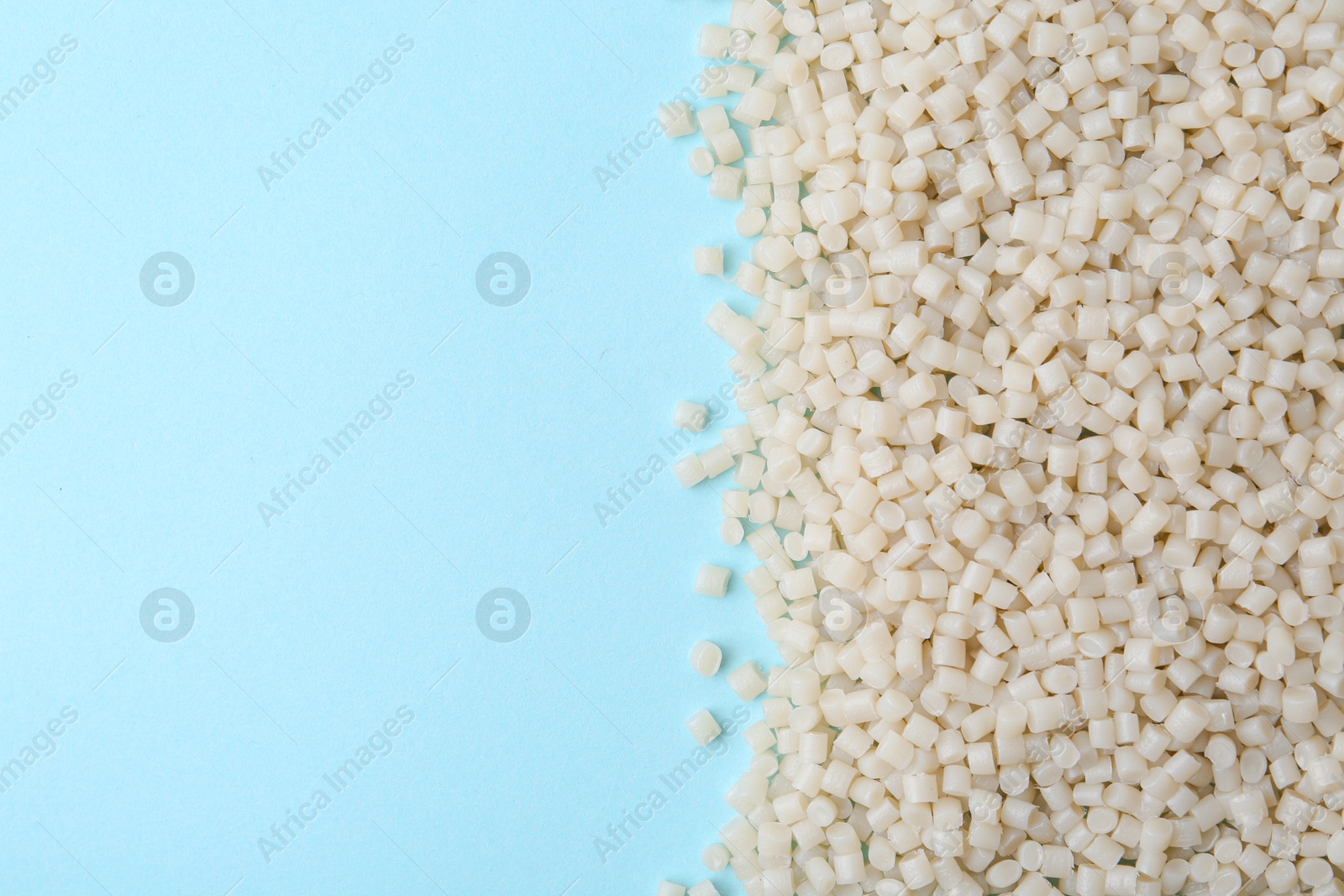 Photo of Pile of plastic granules on light blue background, top view. Space for text