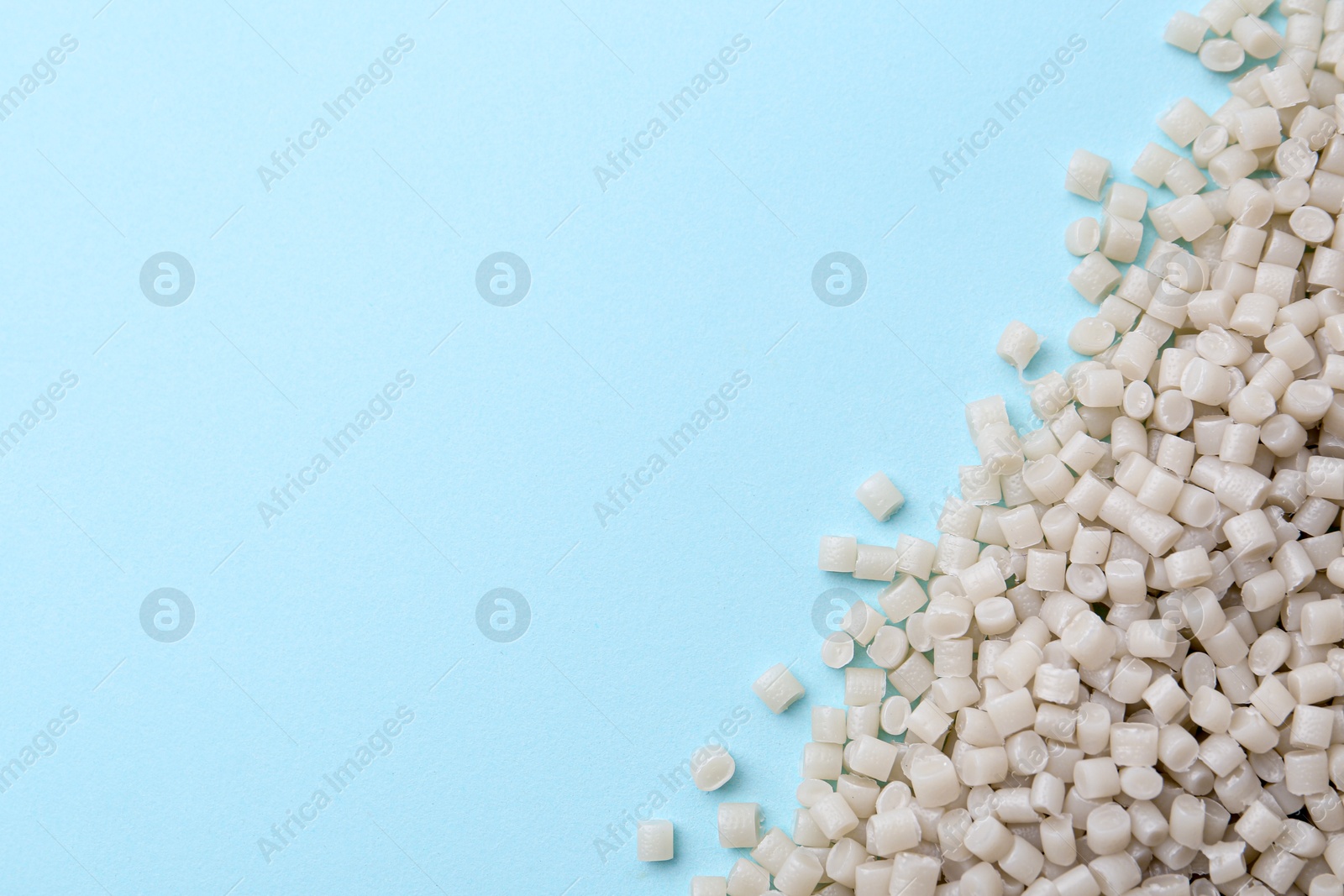 Photo of Pile of plastic granules on light blue background, top view. Space for text