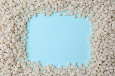 Photo of Frame of plastic granules on light blue background, top view. Space for text